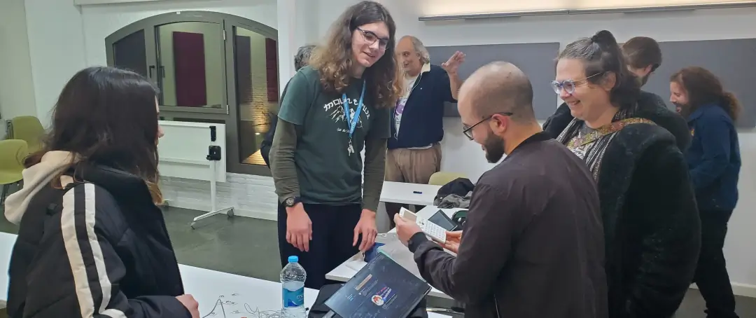 Un grupo de personas reunidas en una de las salas del edificio Las Naves en València, charlando y resolviendo problemas en ordenadores.