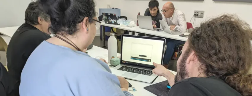 Varias personas delante de un Macbook instalando Linux Mint.