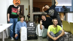 Un grupo de personas haciéndose una foto delante de una lápida falsa de Windows 10, al estilo de un famoso meme sobre la serie Green Arrow.