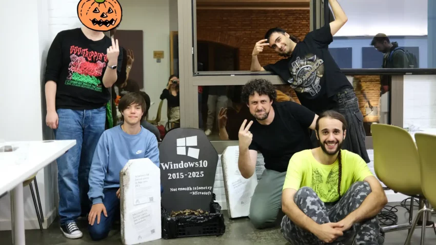 Un grupo de personas haciéndose una foto delante de una lápida falsa de Windows 10, al estilo de un famoso meme sobre la serie Green Arrow.