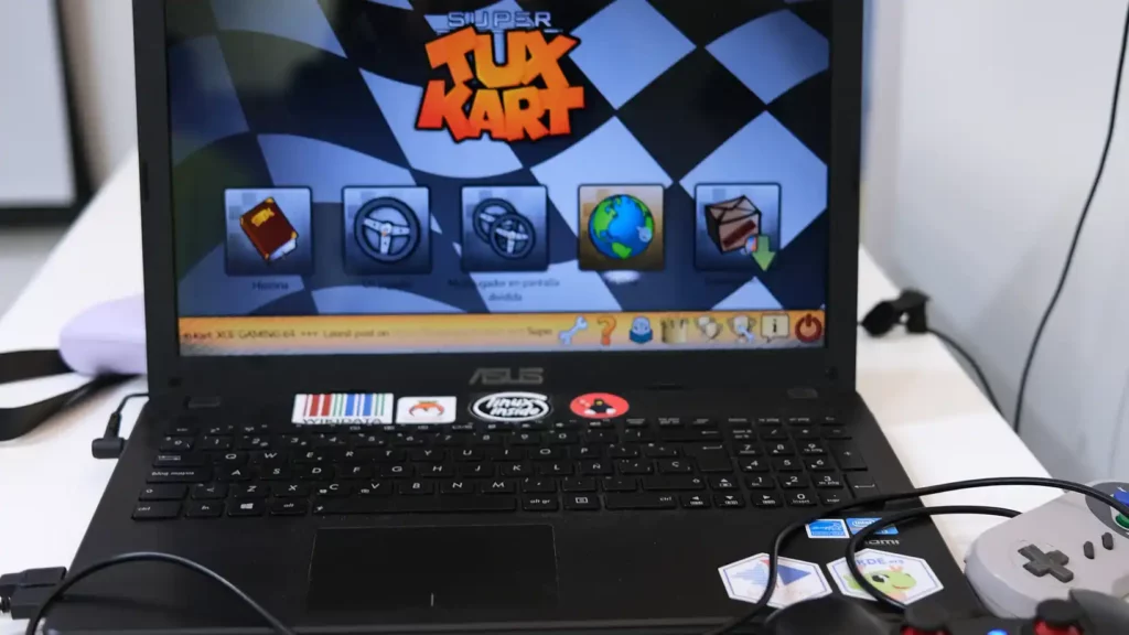 Un ordenador portátil corriendo Super Tux Kart, con un par de mandos de videojuegos conectados.