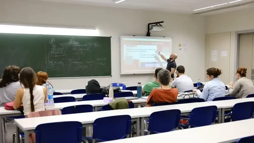 Un grupo de alumnos prestando atención a una presentación proyectada y el presentador.